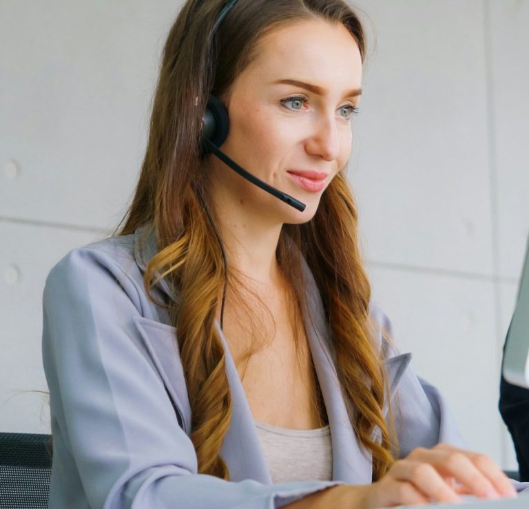 Frau mit Headset tippt an einem Computer in einem modernen Büro.